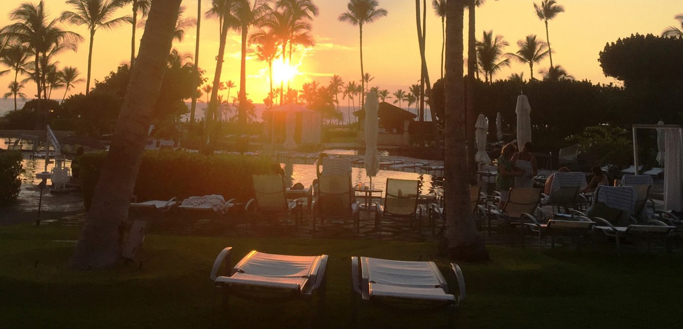 Sunset view by the pool with palm trees and sun loungers