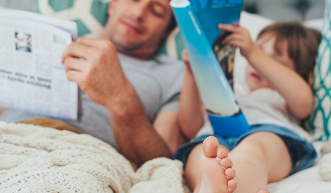 Dad and daughter bonding while reading in bed together