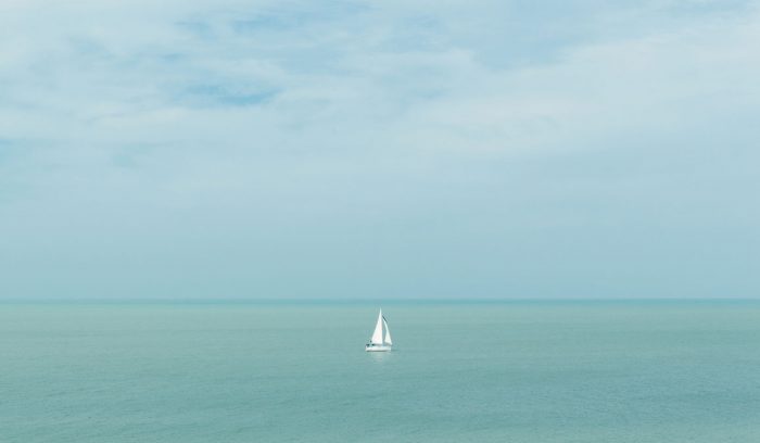 A sailboat on a clear and calm blue sea.