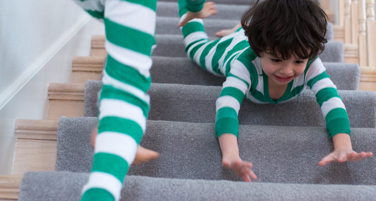 Siblings in pajamas playing by the stairs