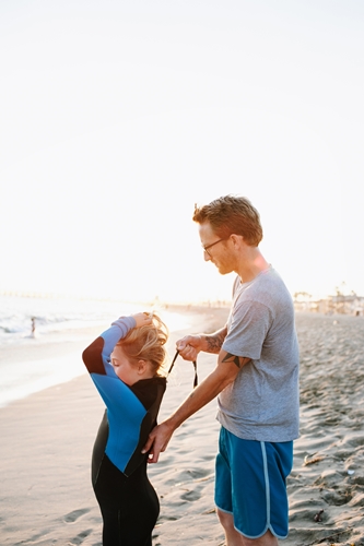 Father zipping up child's wetsuit