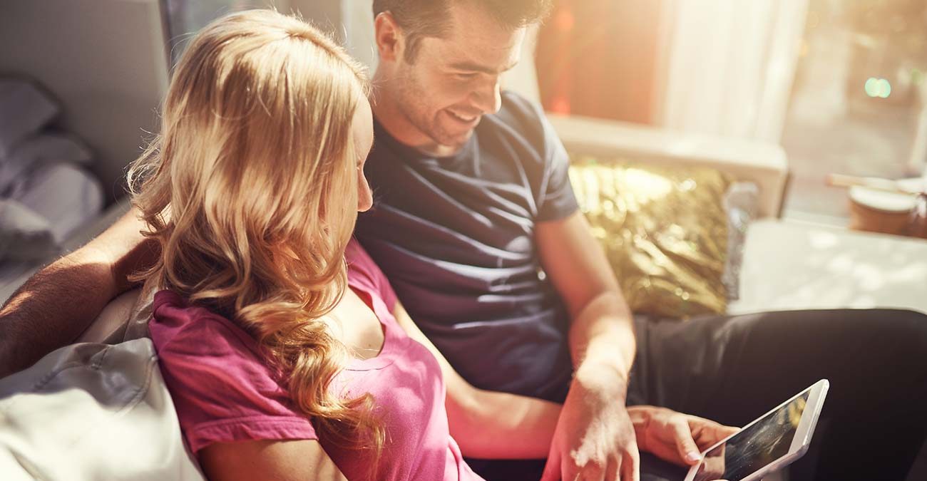 Attractive couple using tablet together on couch at home