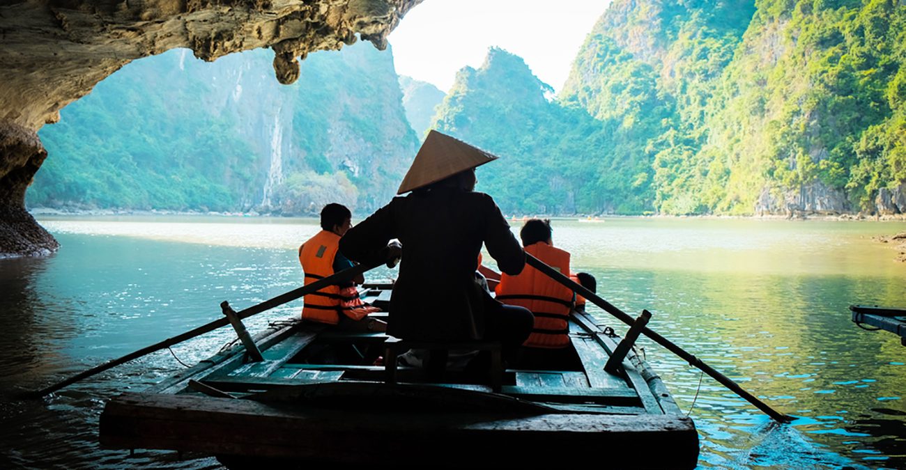 A young girl paddle's a bamboo boat for tourists in the beautiful bay in Vietnam.