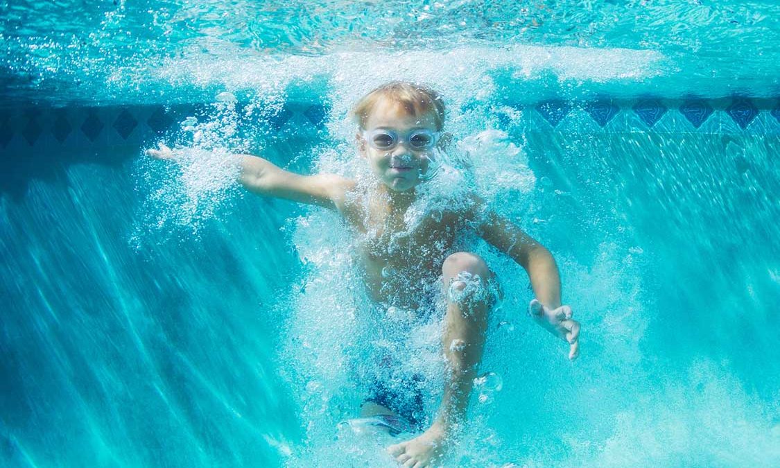 Little boy wearing goggles in the pool