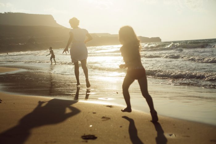 family playing on the beach at sunset