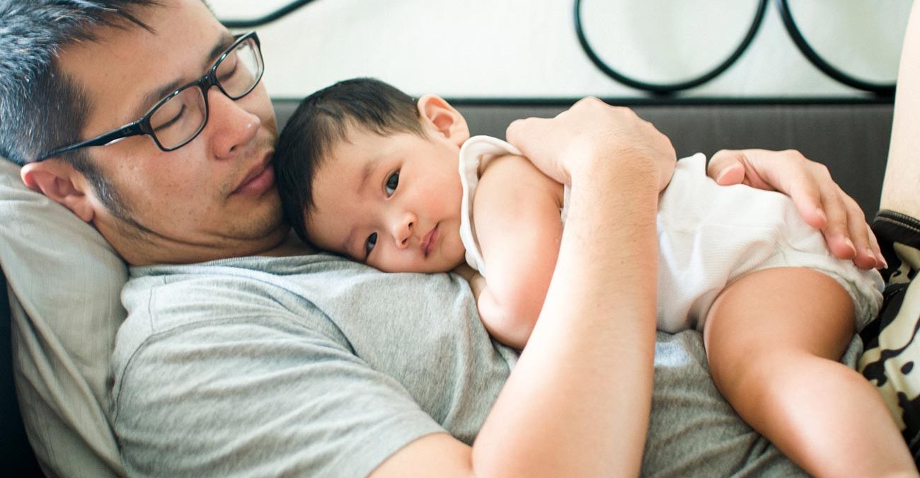 Father cradling his baby son on the couch