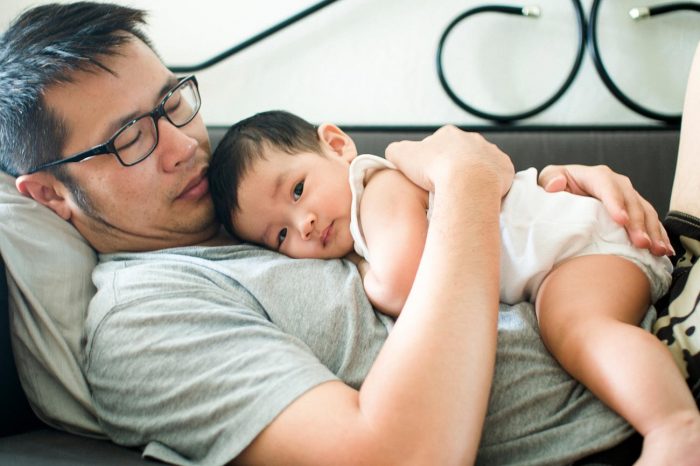 Father cradling his baby son on the couch