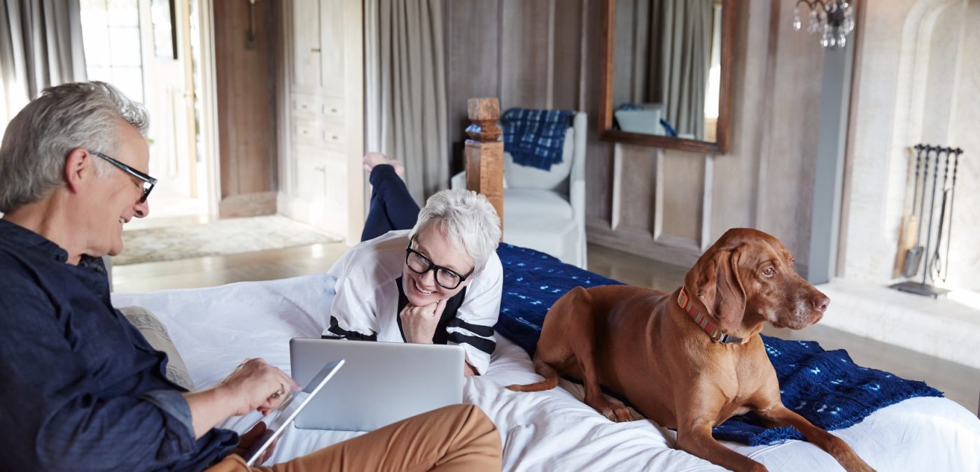 old couple in bed with dog, enjoying retirement