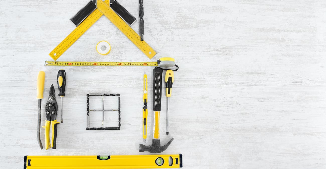 Home tools shaped into a house on a white wooden background