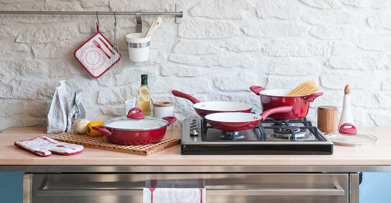 Modern red kitchen behind brick wall with red cookware set