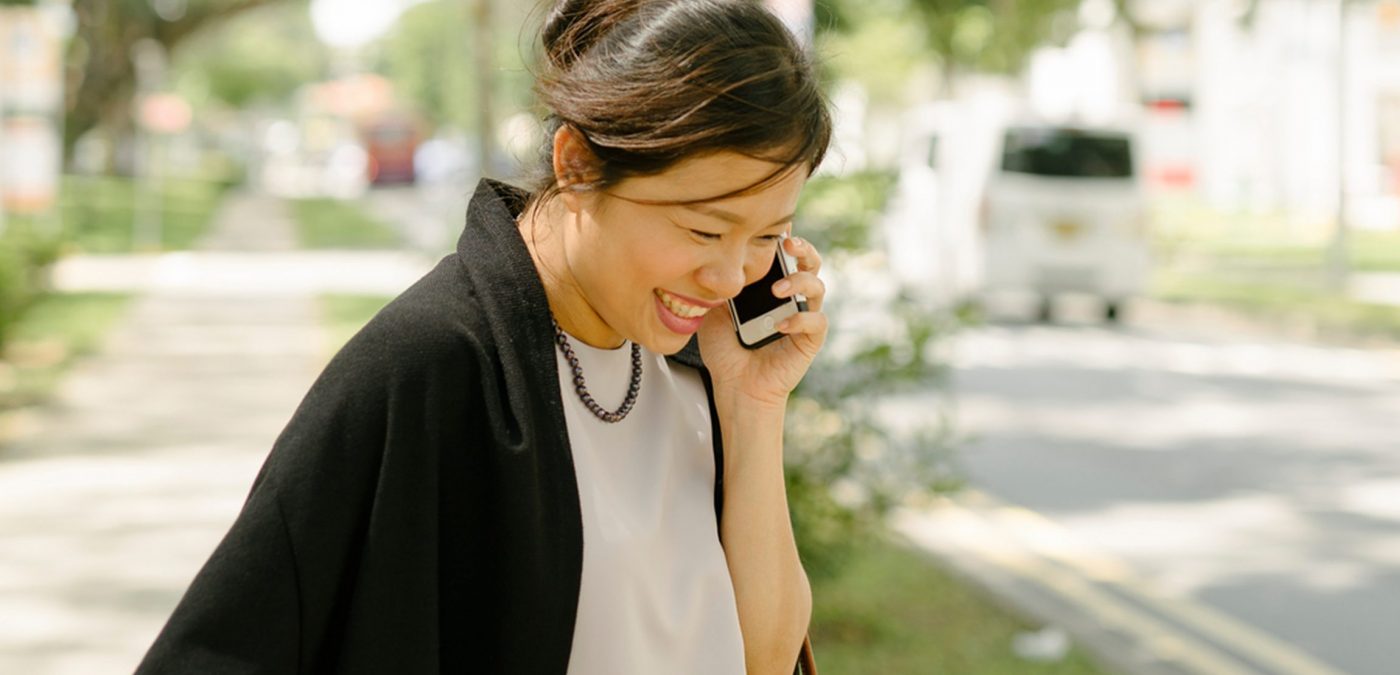 woman approaching curb on phone – meeting her uber driver, saving money on transport