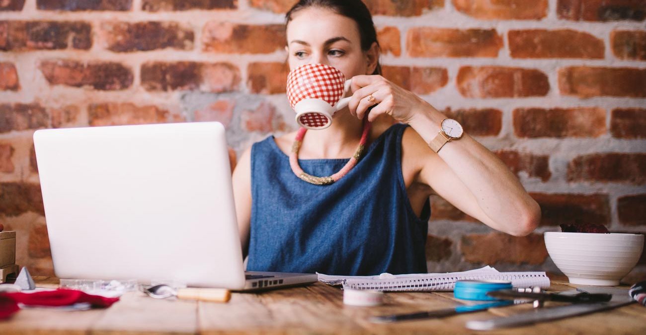 woman sipping tea whilst sorting her finances