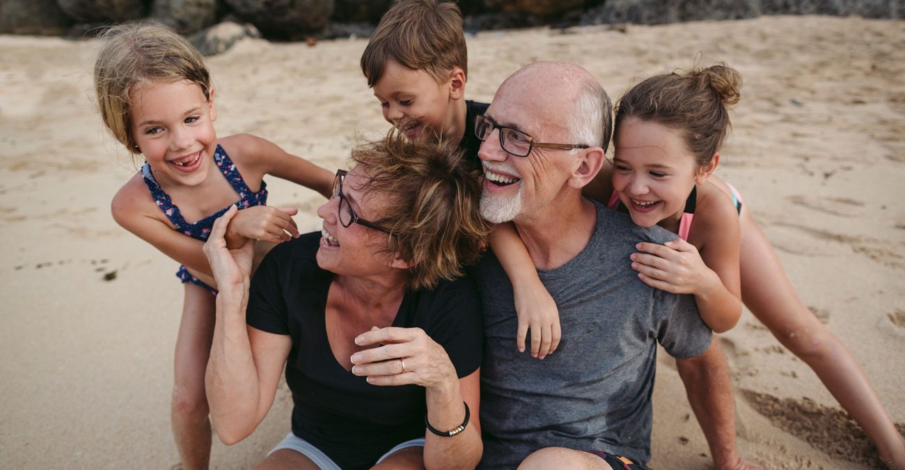 A couple with their grandkids on the beach.