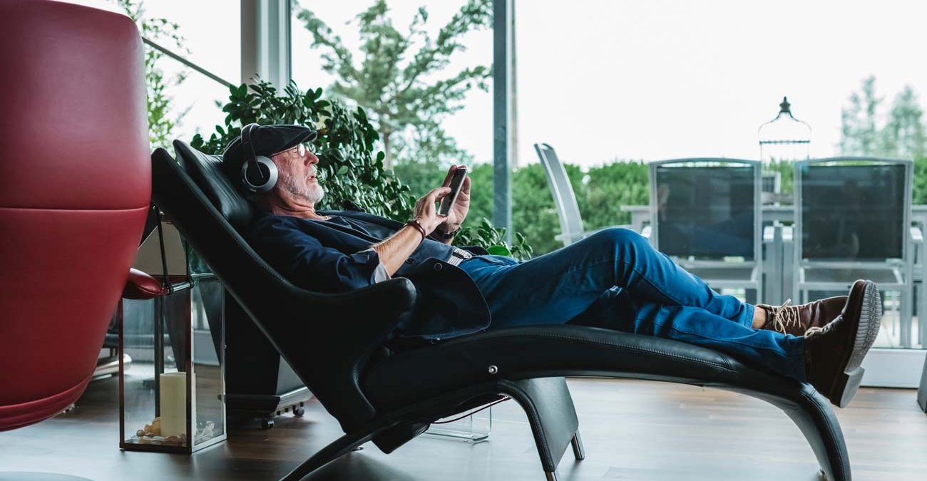 Modern senior man listening to music at home