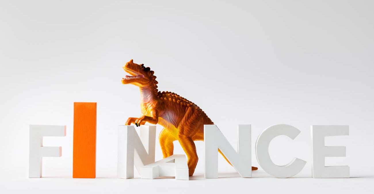 dinosaur figure and finance letters being crushed