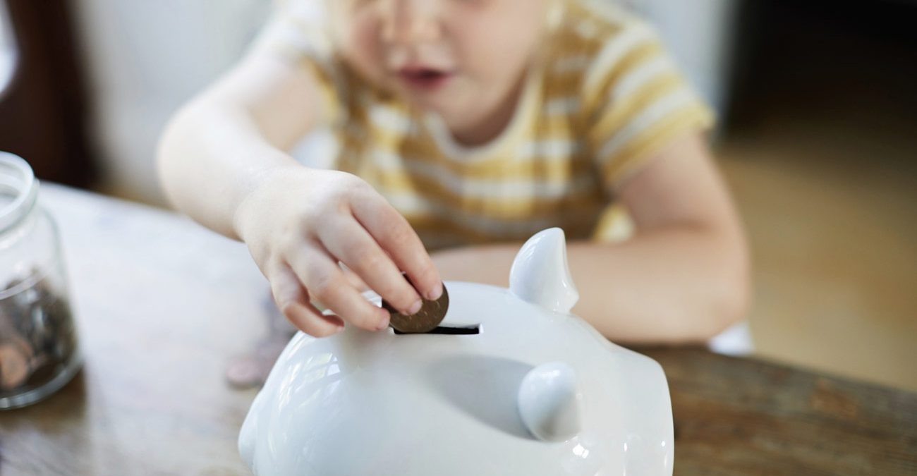 Child putting money into a piggy bank