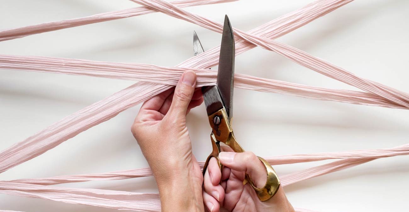 hands using scissors to cut a tangle of silk ribbon