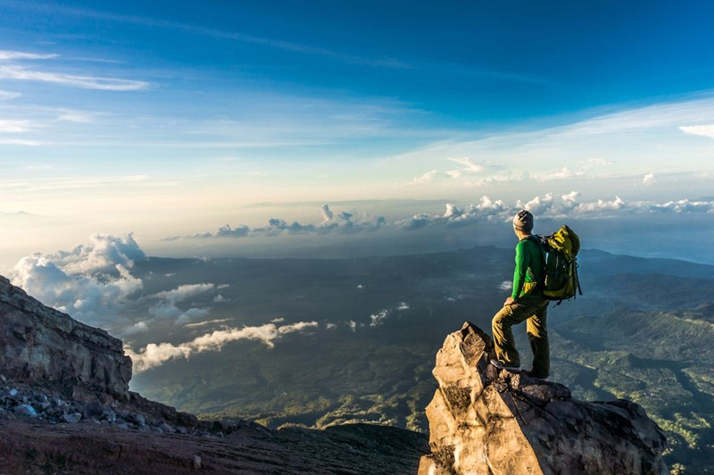 man on top of the mountain peak