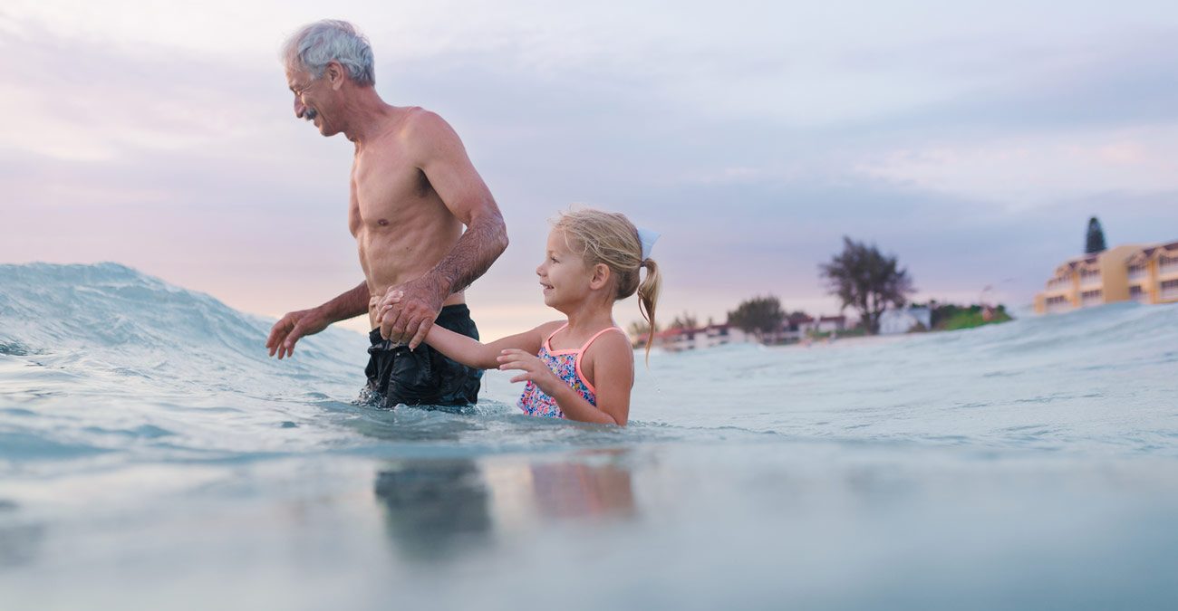 little girl and grandpa going into the ocean