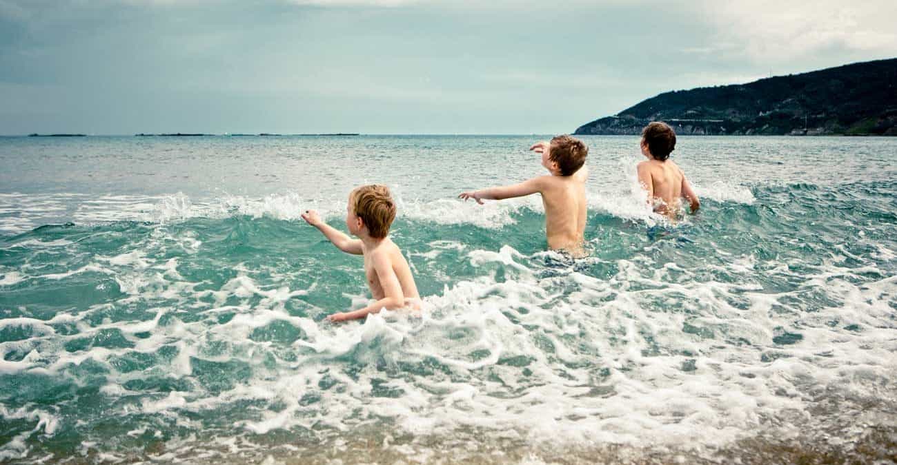 Kids playing in the cold surf at a beach in the Spring.