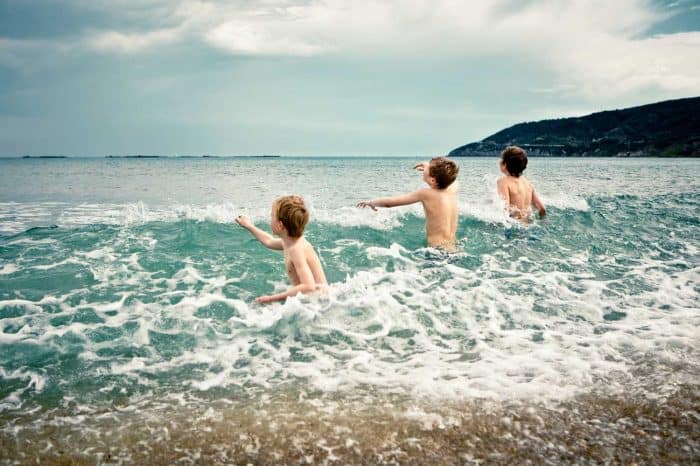 Kids playing in the cold surf at a beach in the Spring.