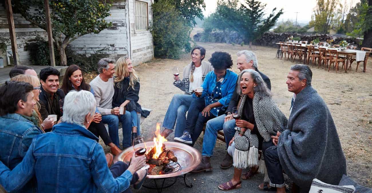 Group of friends and family relaxing around a fire pit at a farm