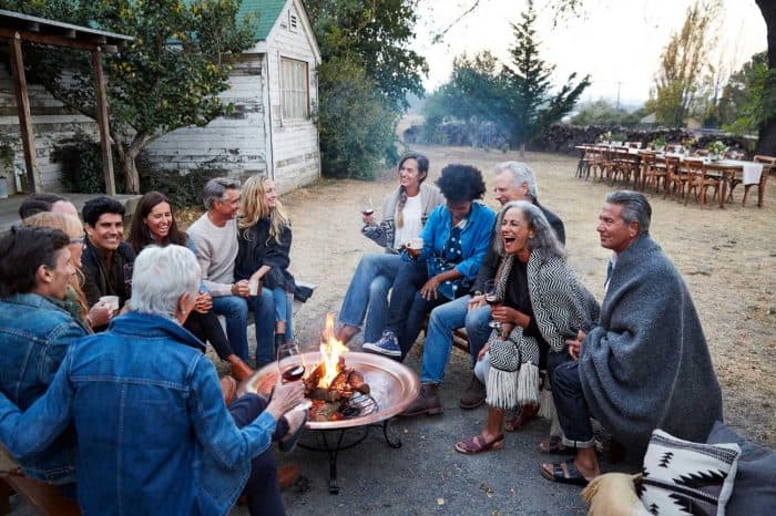 Group of friends and family relaxing around a fire pit at a farm