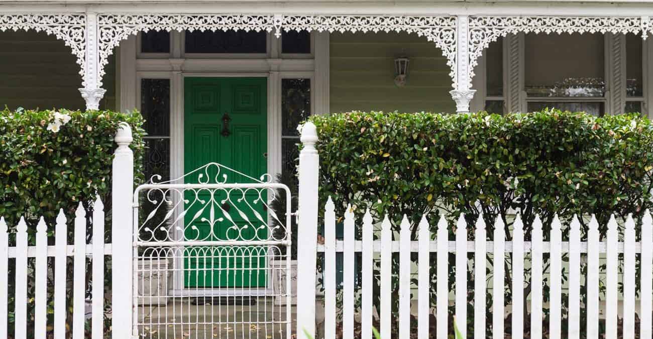 traditional weatherboard house with picketet fence and a hedge