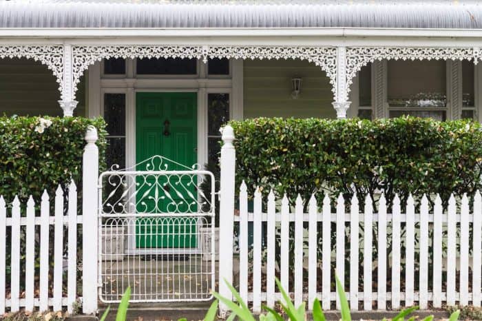 traditional weatherboard house with picketet fence and a hedge