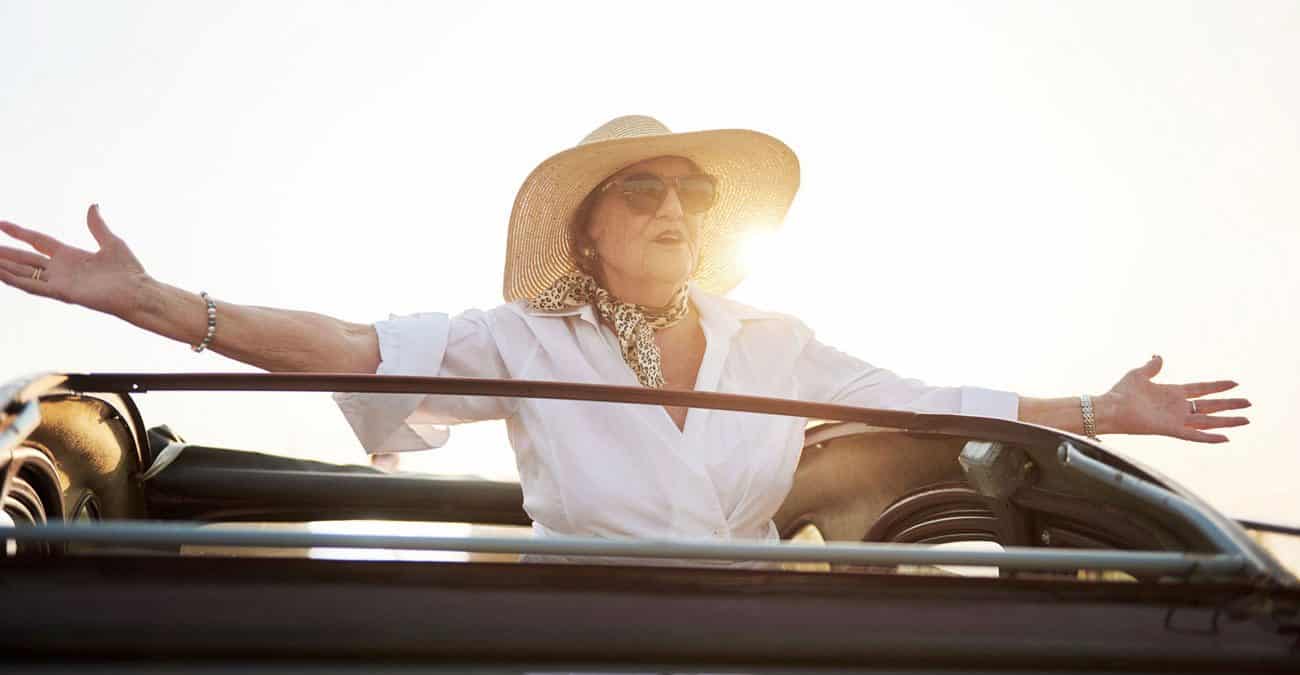 Modern grandmother on the roof of an old car.