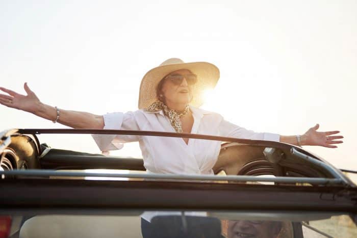 Modern grandmother on the roof of an old car.