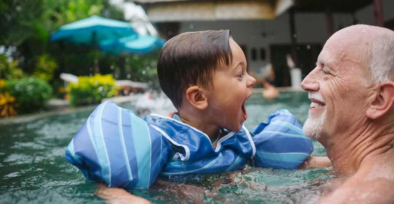 Happy, energetic grandpa playing with grandchild in outdoor pool