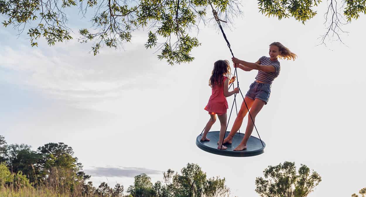 2 girls playing on a swing